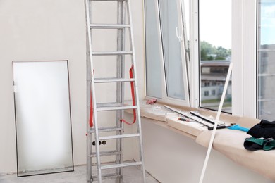 Folding ladder, tools and double glazing indoors. Window installation