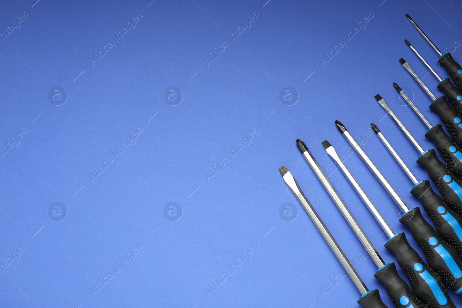 Photo of Set of screwdrivers on blue background, flat lay. Space for text