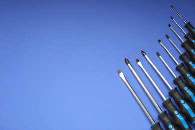 Photo of Set of screwdrivers on blue background, flat lay. Space for text