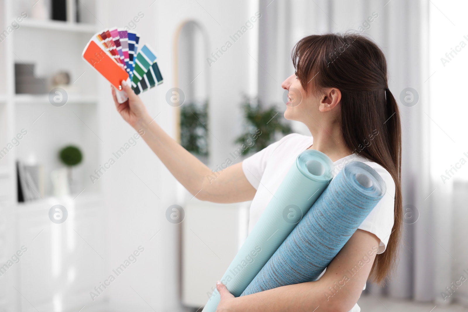 Photo of Woman with wallpaper rolls and color palette in room