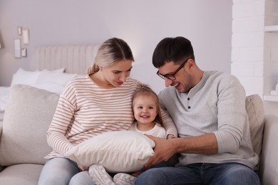 Photo of Family with little daughter spending time together on sofa at home