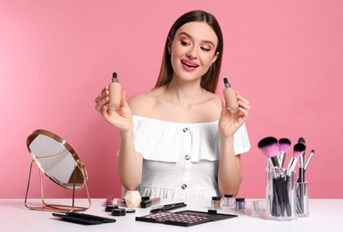 Photo of Beauty blogger showing bottles of foundation on pink background