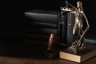 Symbol of fair treatment under law. Statue of Lady Justice near books and gavel on wooden table, space for text.