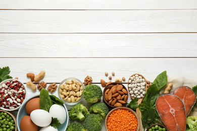 Products rich in protein on white wooden table, flat lay. Space for text