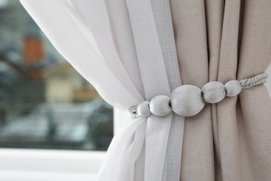 Photo of Draped window curtains with tieback in room, space for text. Home interior