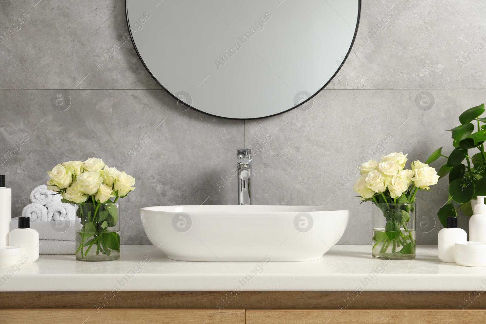 Photo of Beautiful roses and bath accessories near sink in bathroom