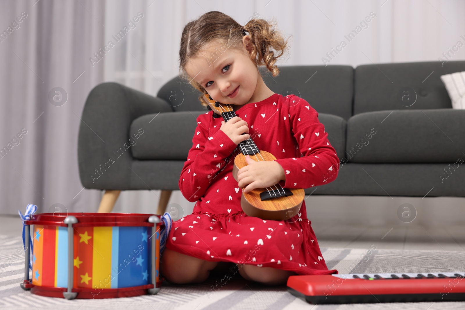 Photo of Little girl playing toy guitar at home