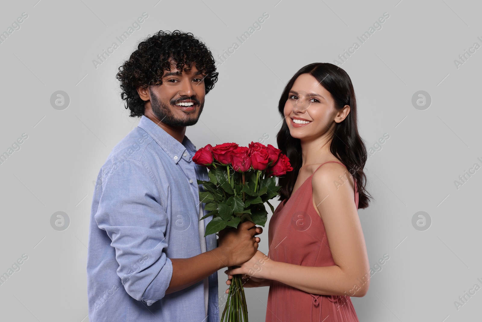 Photo of International dating. Happy couple with bouquet of roses on light grey background