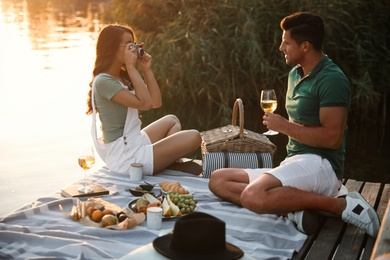 Photo of Woman taking picture of boyfriend on pier at picnic