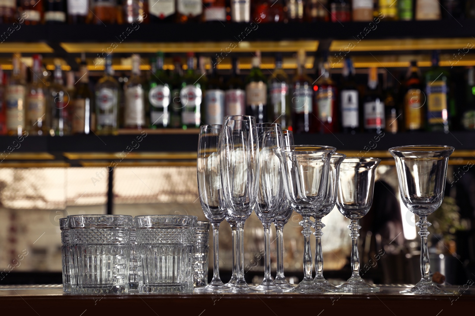 Photo of Different empty clean glasses on counter in bar