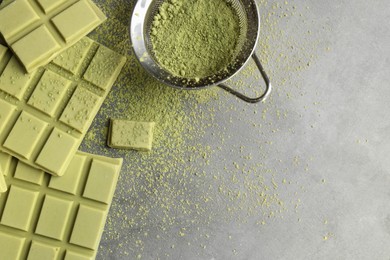 Photo of Pieces of tasty matcha chocolate bars and powder on grey textured table, flat lay. Space for text