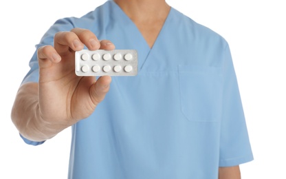 Male doctor holding pills on white background, closeup. Medical object