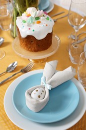 Festive table setting with painted egg, traditional Easter cake and cutlery