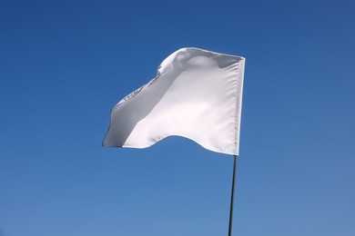 White flag fluttering against blue sky on sunny day