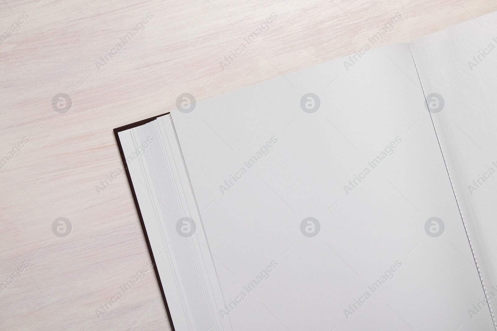 Photo of One open photo album on wooden table, top view