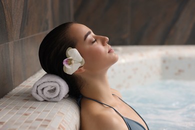 Photo of Beautiful woman with orchid flower relaxing in spa swimming pool