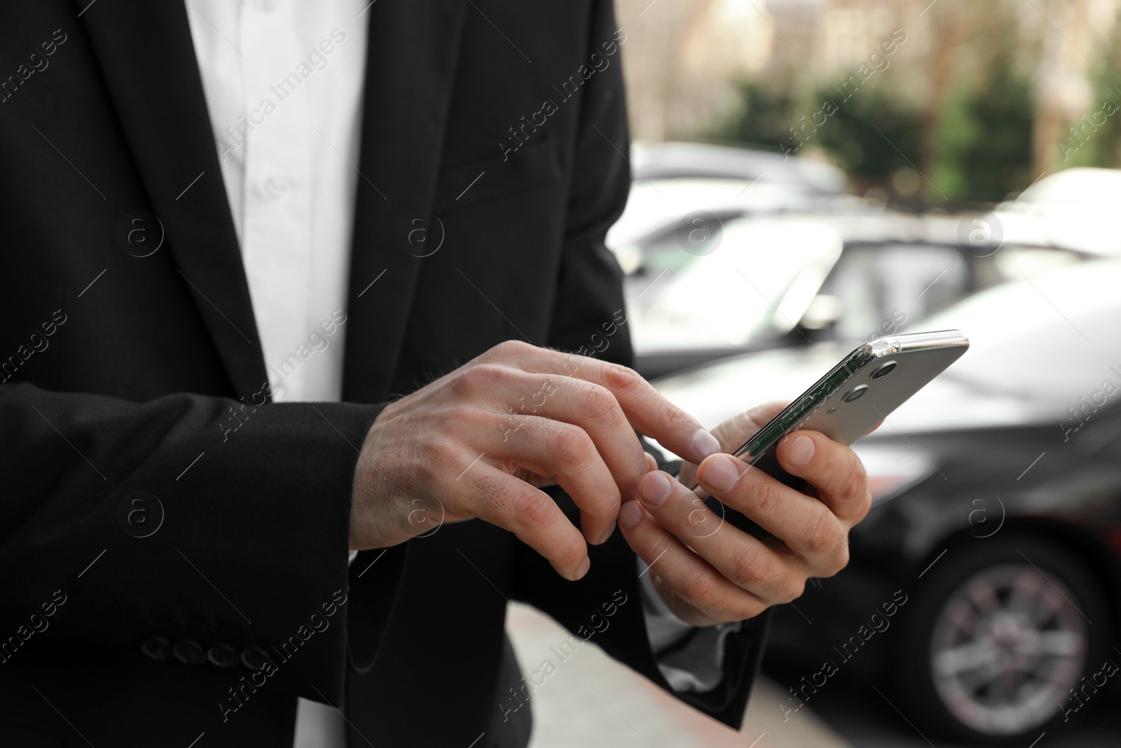 Photo of Businessman ordering taxi with smartphone on city street, closeup