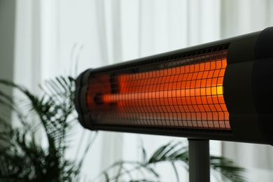 Photo of Modern electric infrared heater in room, closeup