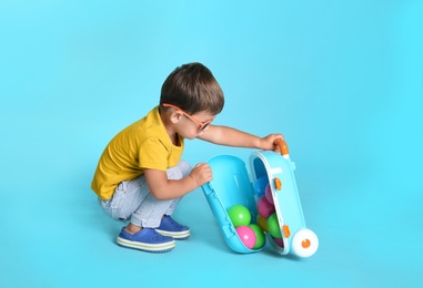 Cute little boy with sunglasses and suitcase on blue background, space for text