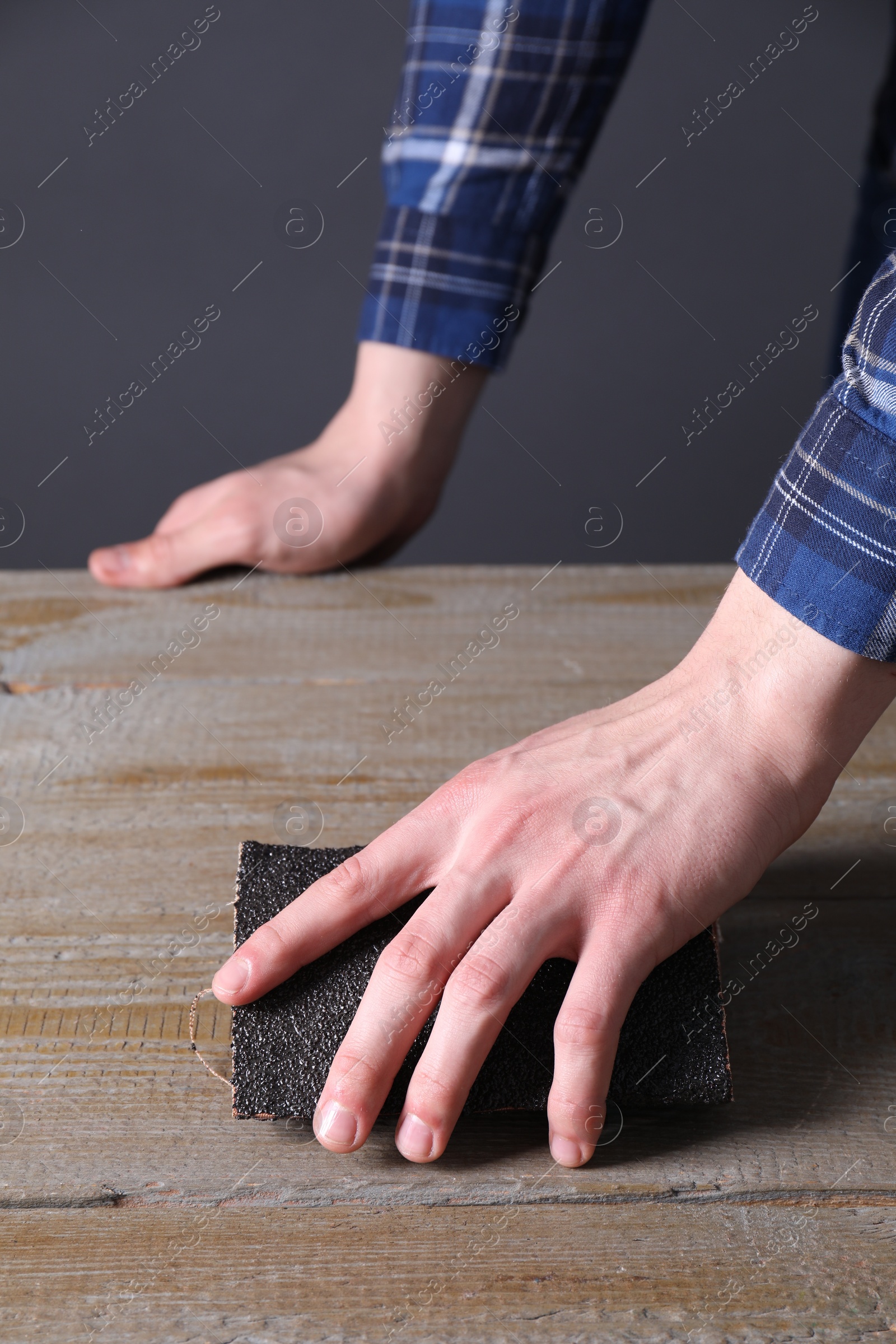 Photo of Man polishing wooden table with sandpaper, closeup