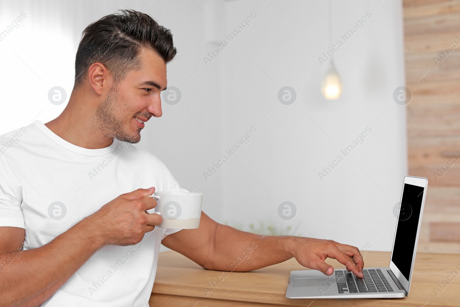 Photo of Portrait of handsome young man with laptop at home