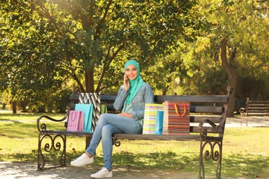 Muslim woman talking on phone in park