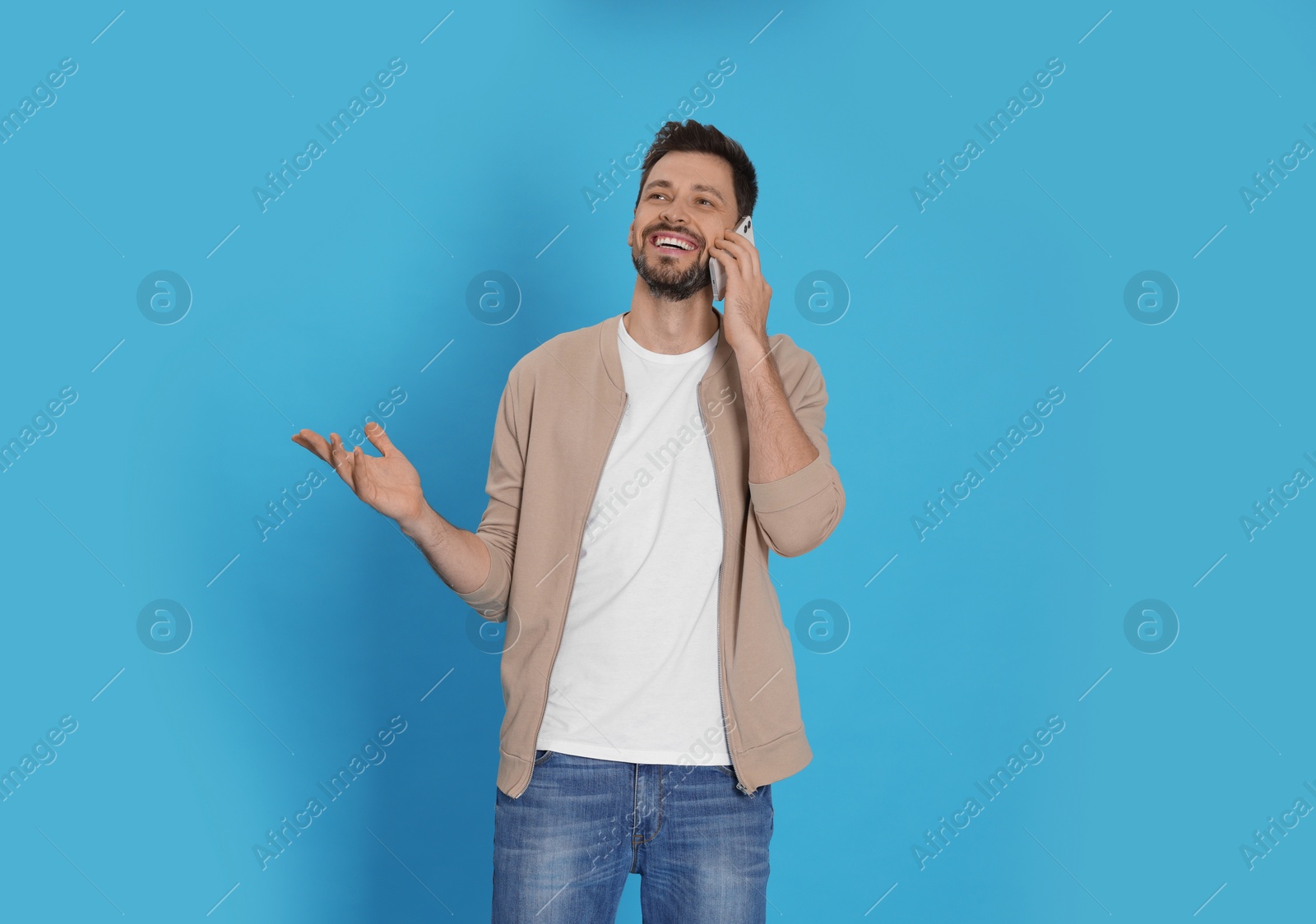 Photo of Man talking on phone against light blue background