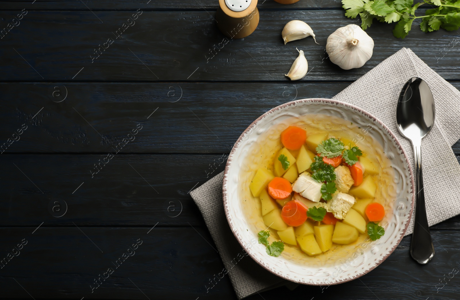 Photo of Homemade chicken soup served on wooden table, top view with space for text