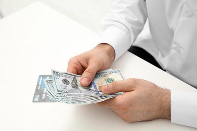 Man with money at table indoors, closeup