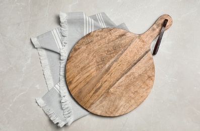 Photo of Wooden board and napkin on grey table, top view. Cooking utensil