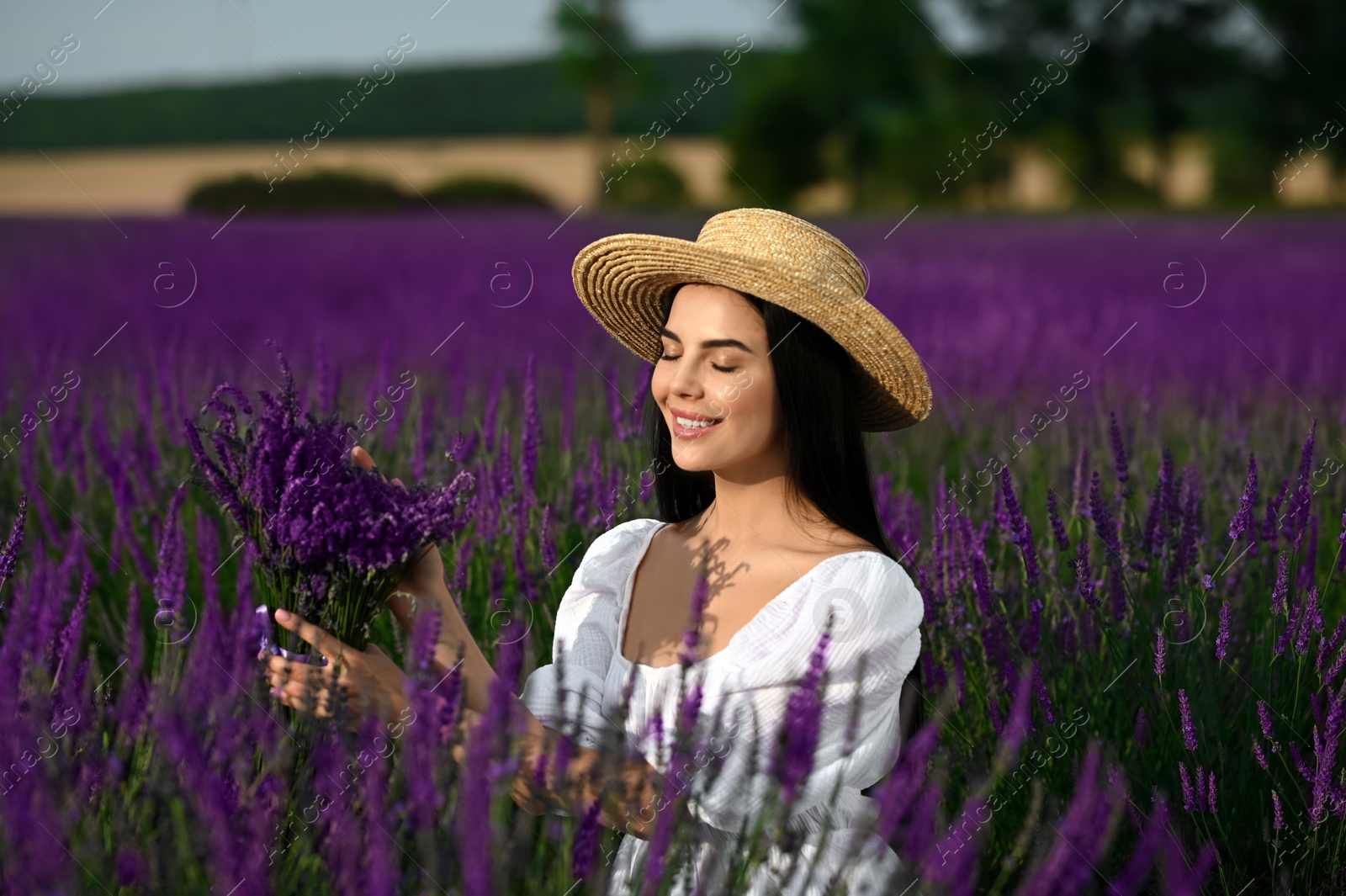 Photo of Beautiful young woman with bouquet in lavender field