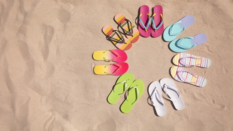 Photo of Flat lay composition with flip flops on sand, space for text. Summer beach accessories