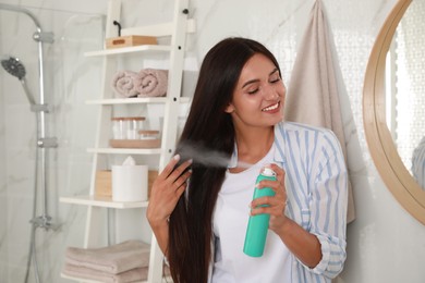Photo of Woman applying dry shampoo onto her hair in bathroom