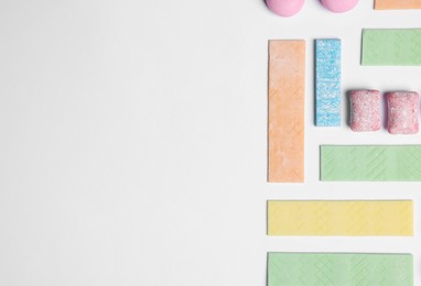 Photo of Different tasty colorful bubble gums on white background, flat lay. Space for text