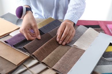 Photo of Young woman choosing among upholstery fabric samples, closeup. Interior design