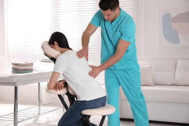 Woman receiving massage in modern chair indoors