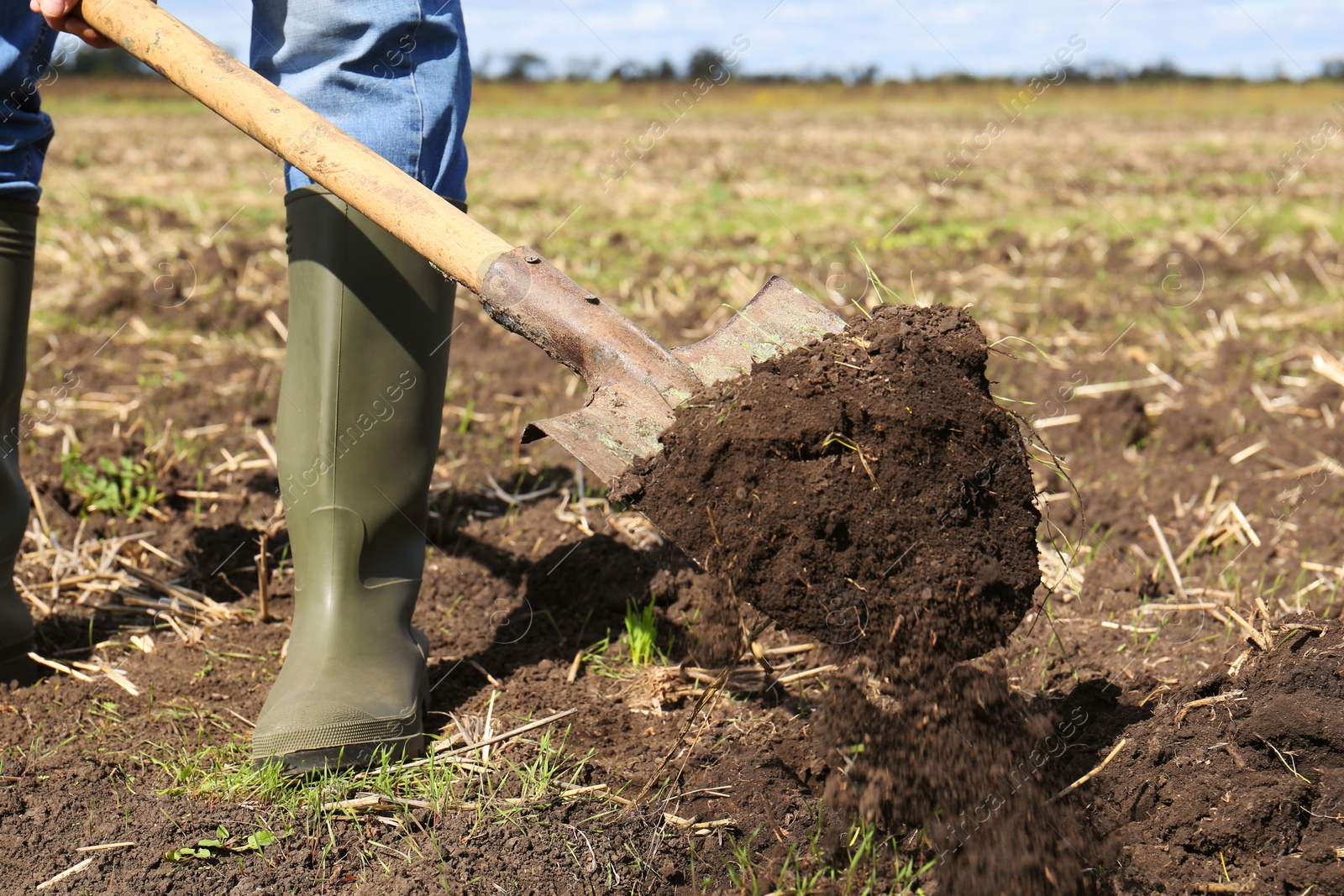 Photo of Man digging soil with shovel in field, closeup