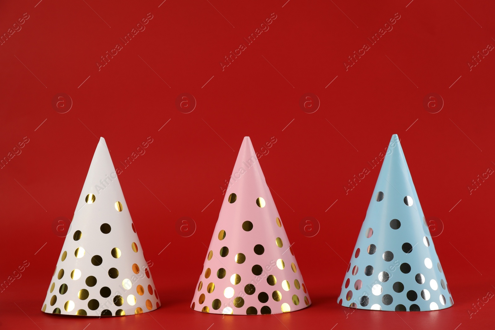 Photo of Bright party hats on red background. Festive accessory