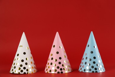 Photo of Bright party hats on red background. Festive accessory