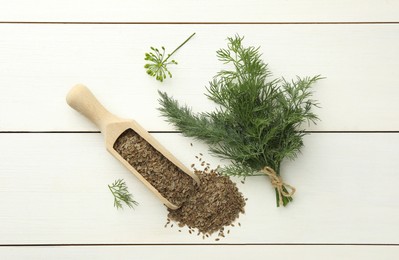 Photo of Dry seeds and fresh dill on white wooden table, flat lay