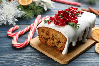 Photo of Traditional classic Christmas cake decorated with cranberries, pomegranate seeds and rosemary on blue wooden table