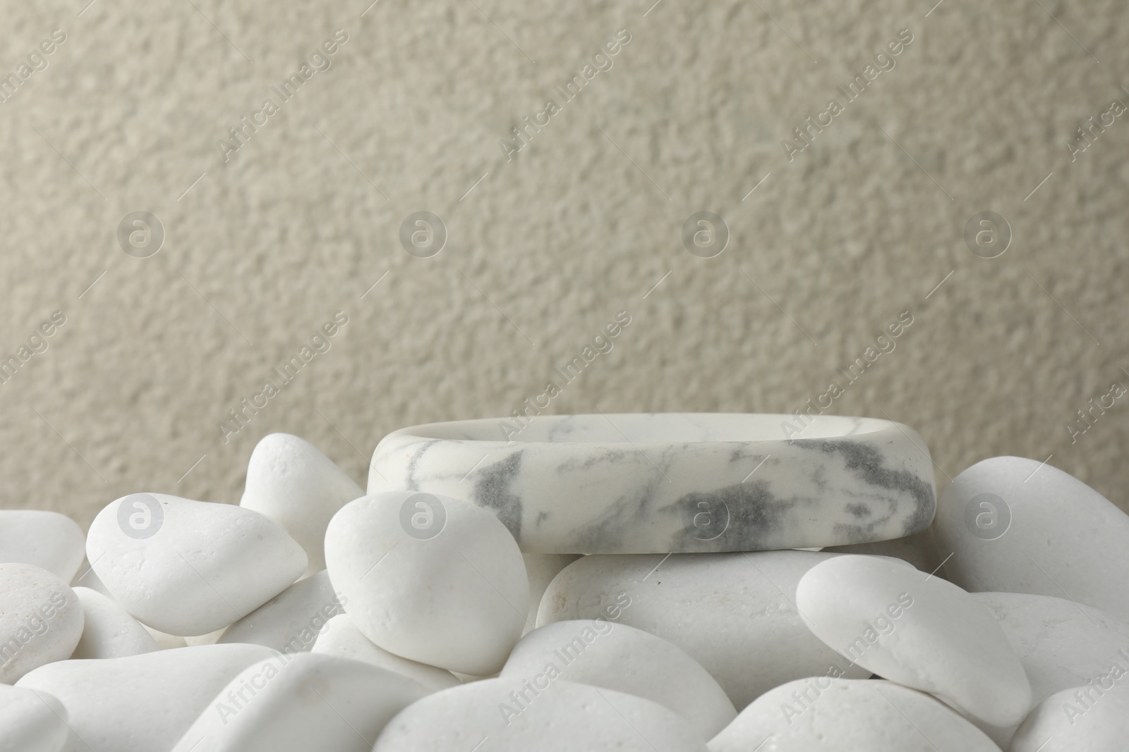 Photo of Presentation for product. Stone podium and white pebbles on blurred background. Space for text