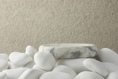 Photo of Presentation for product. Stone podium and white pebbles on blurred background. Space for text