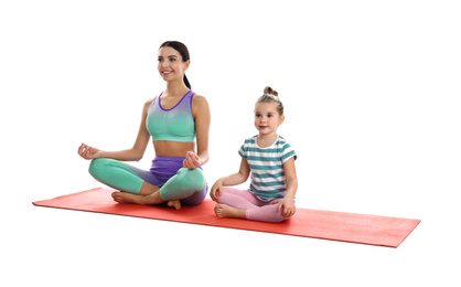 Woman and daughter in fitness clothes meditating together on white background