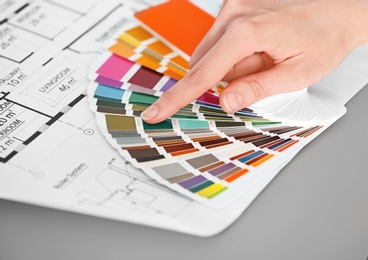 Photo of Female designer working with color palette samples at table