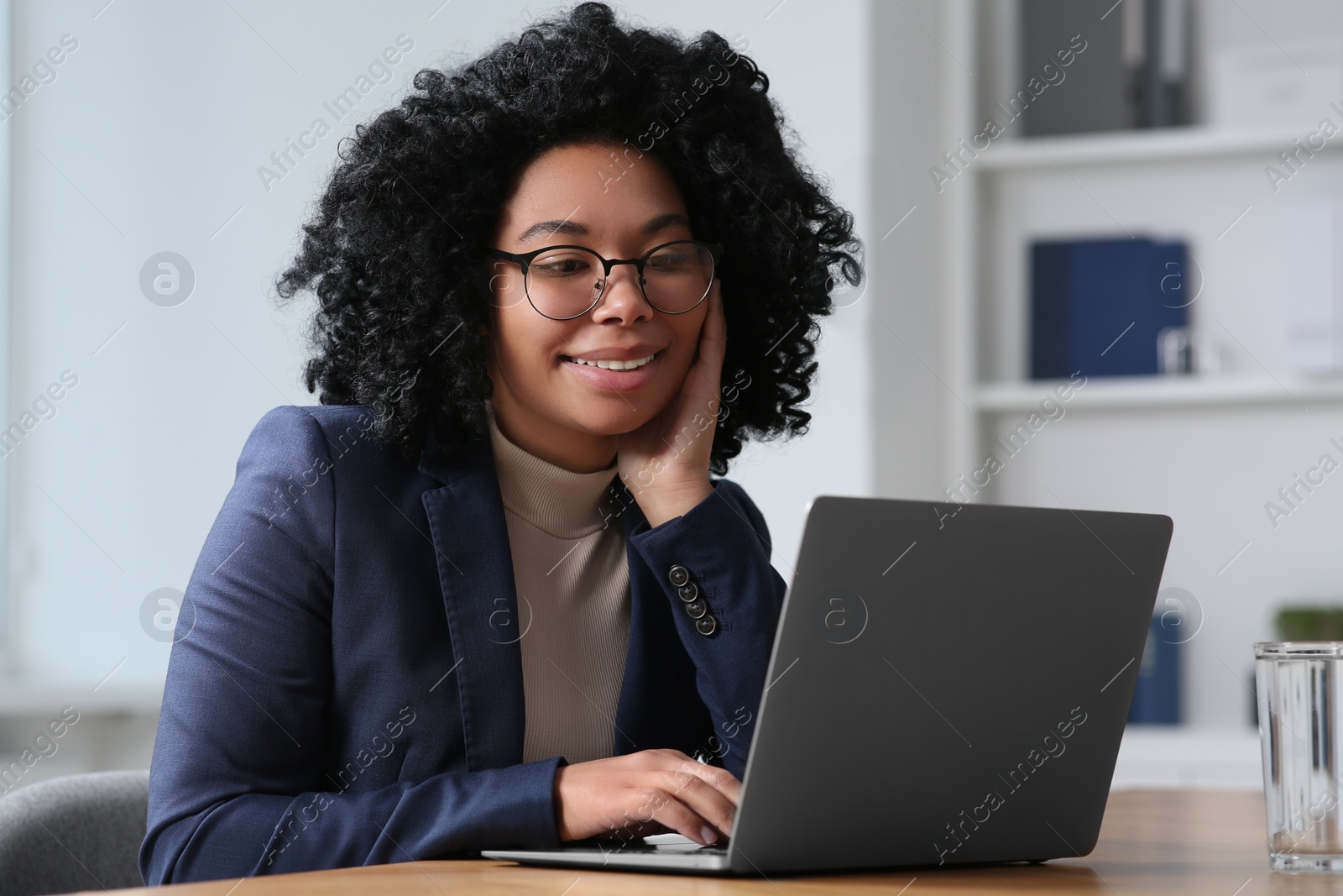 Photo of Young woman working on laptop at table in office