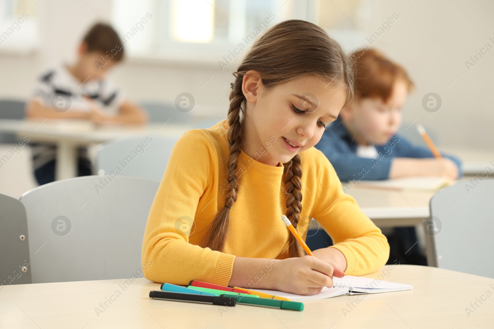 Photo of Smiling little girl studying in classroom at school