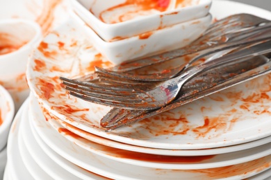 Stack of dirty dishes with cutlery, closeup