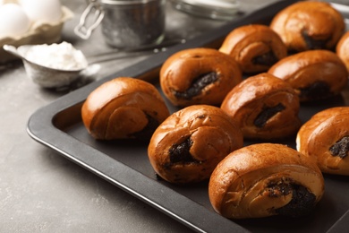 Tray with freshly baked poppy seed buns on table