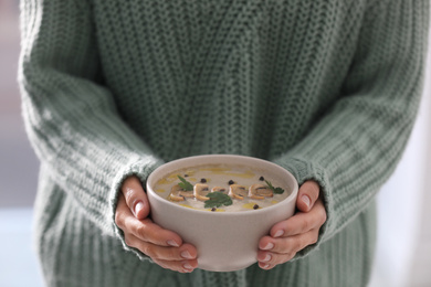 Young woman with bowl of cream soup, closeup